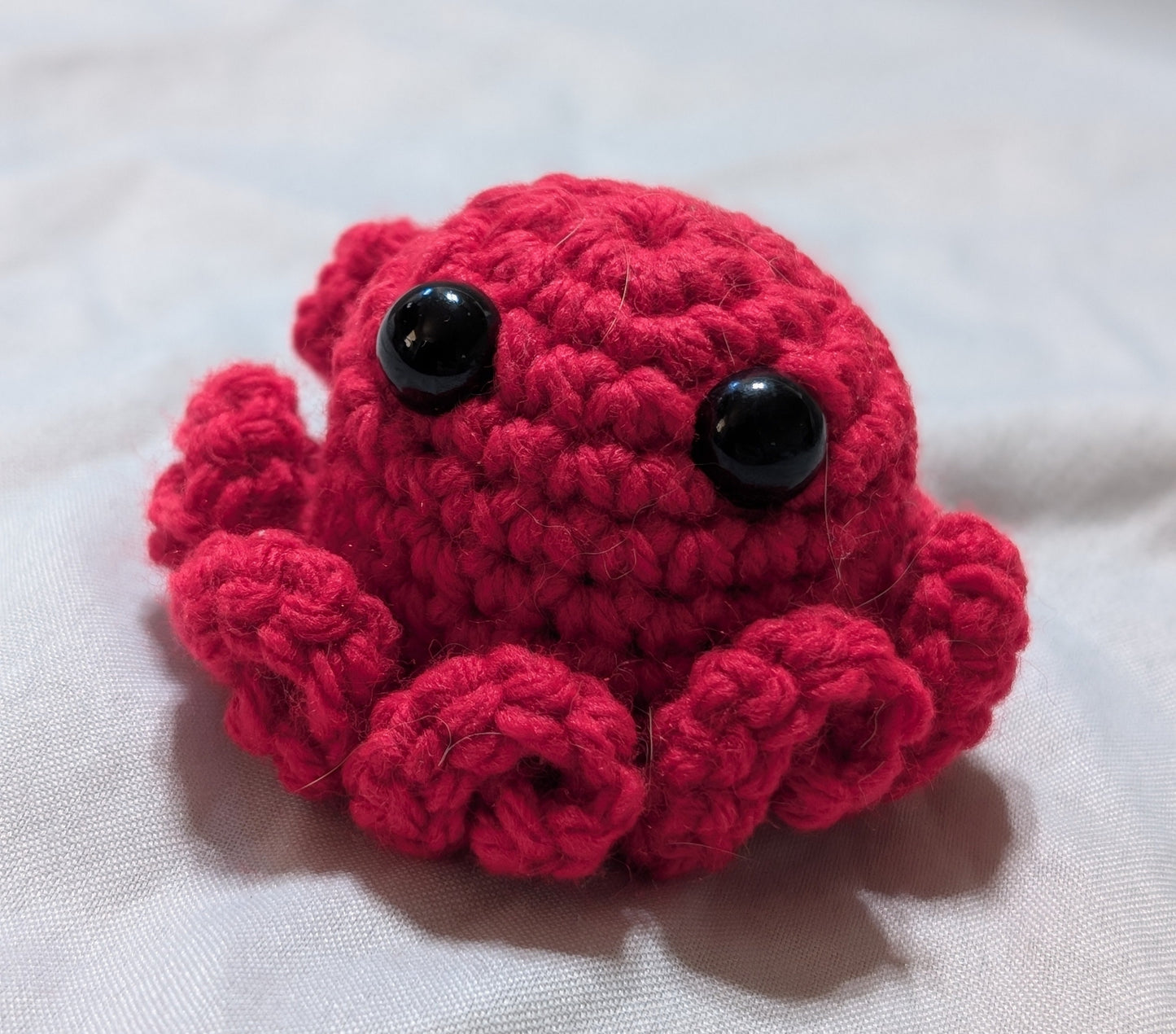 Red crochet octopus toy on a white surface