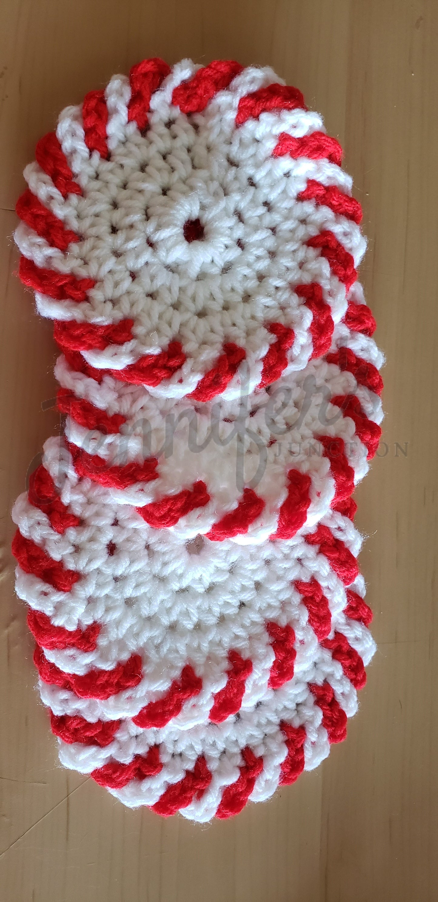 Stack of red and white crocheted coasters on a wooden surface