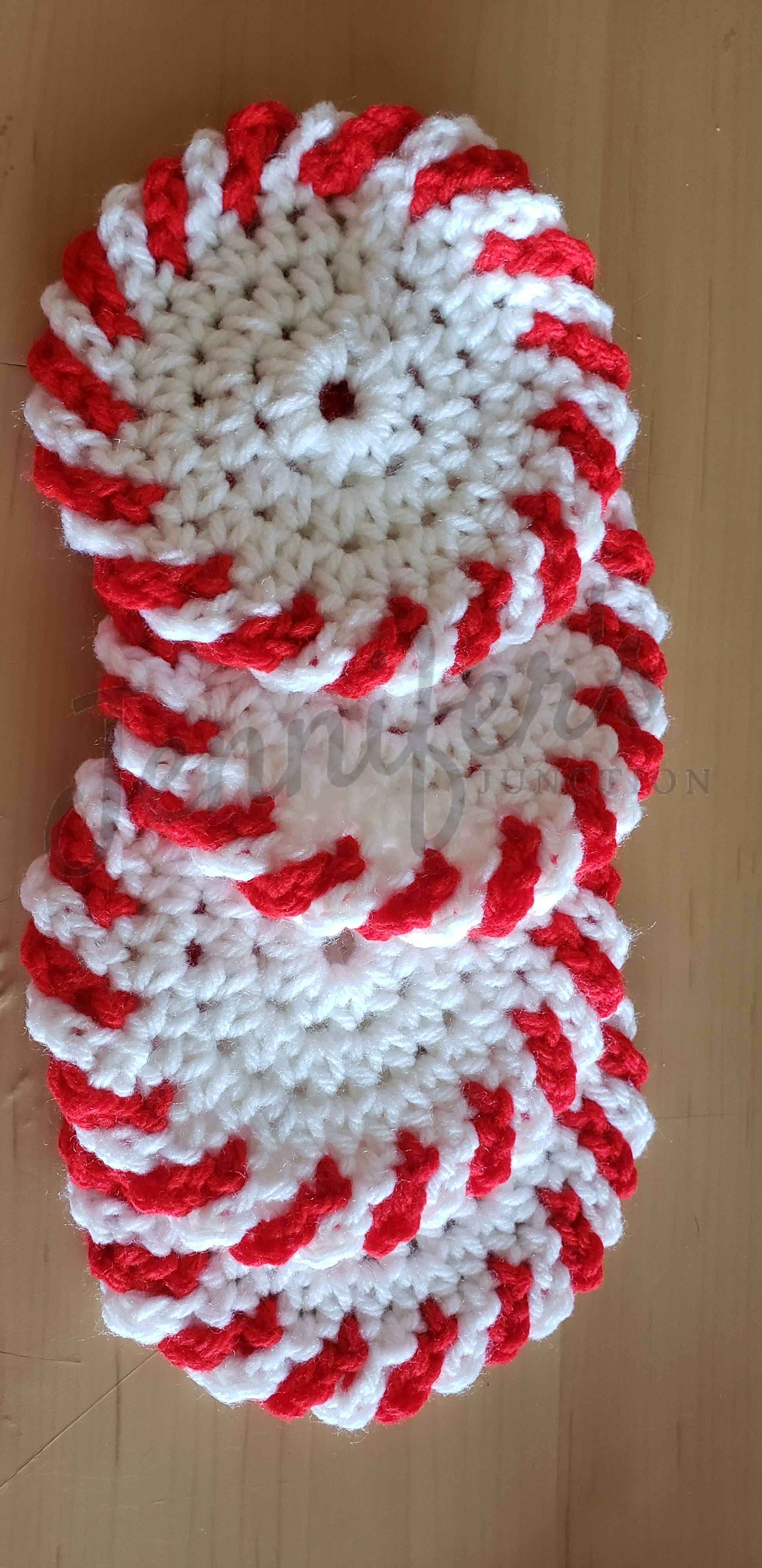 Stack of red and white crocheted coasters on a wooden surface
