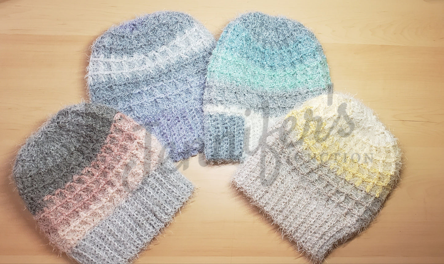 Four crochet hats in different colors on a wooden surface