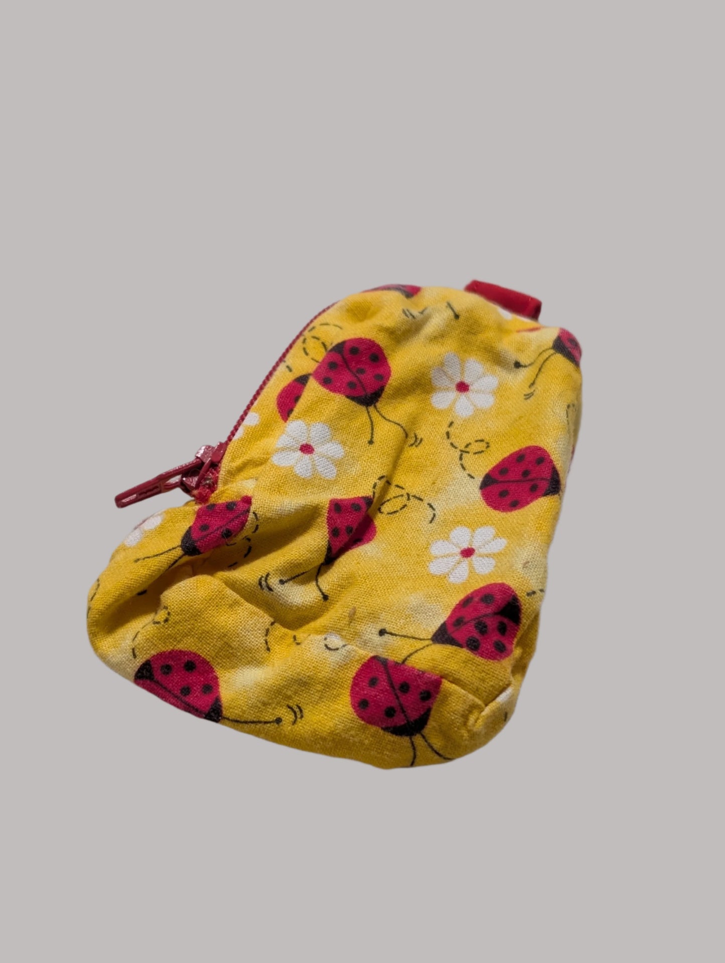 Yellow pouch with ladybug pattern on a light gray fabric background
